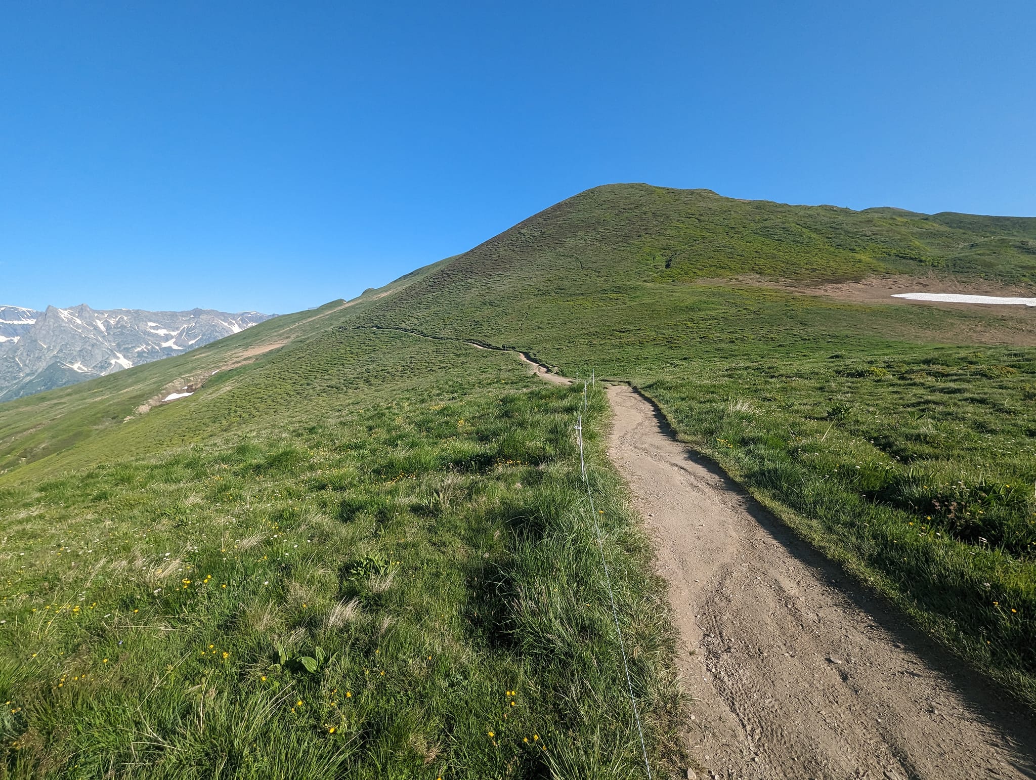 På tur fra passet går stien langs gresskledde fjellsider inn i Frankrike.
